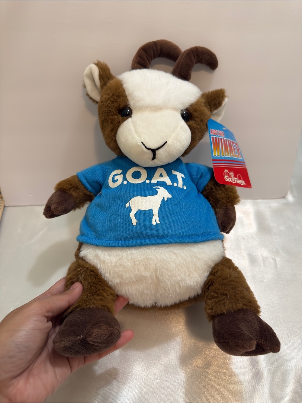 Six Flags goat plush wearing a blue "G.O.A.T.”